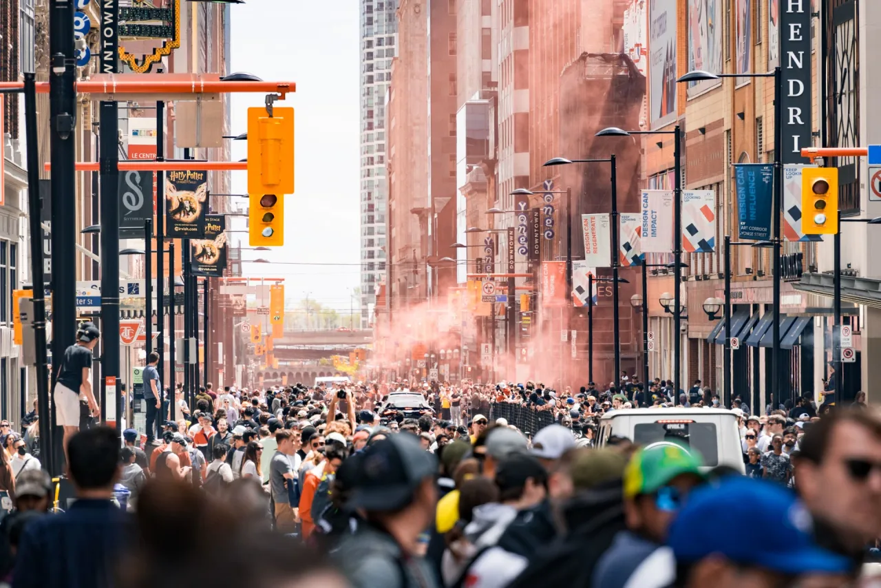 A crowded city street filled with people, signs, and traffic.